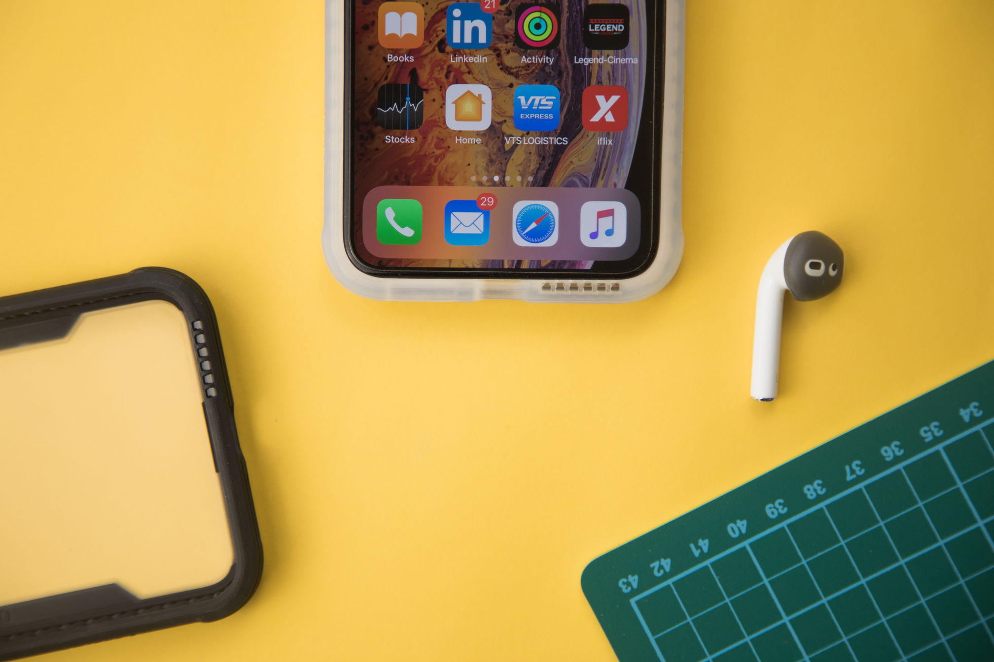 Modern smartphone on yellow surface near earbud and phone cover